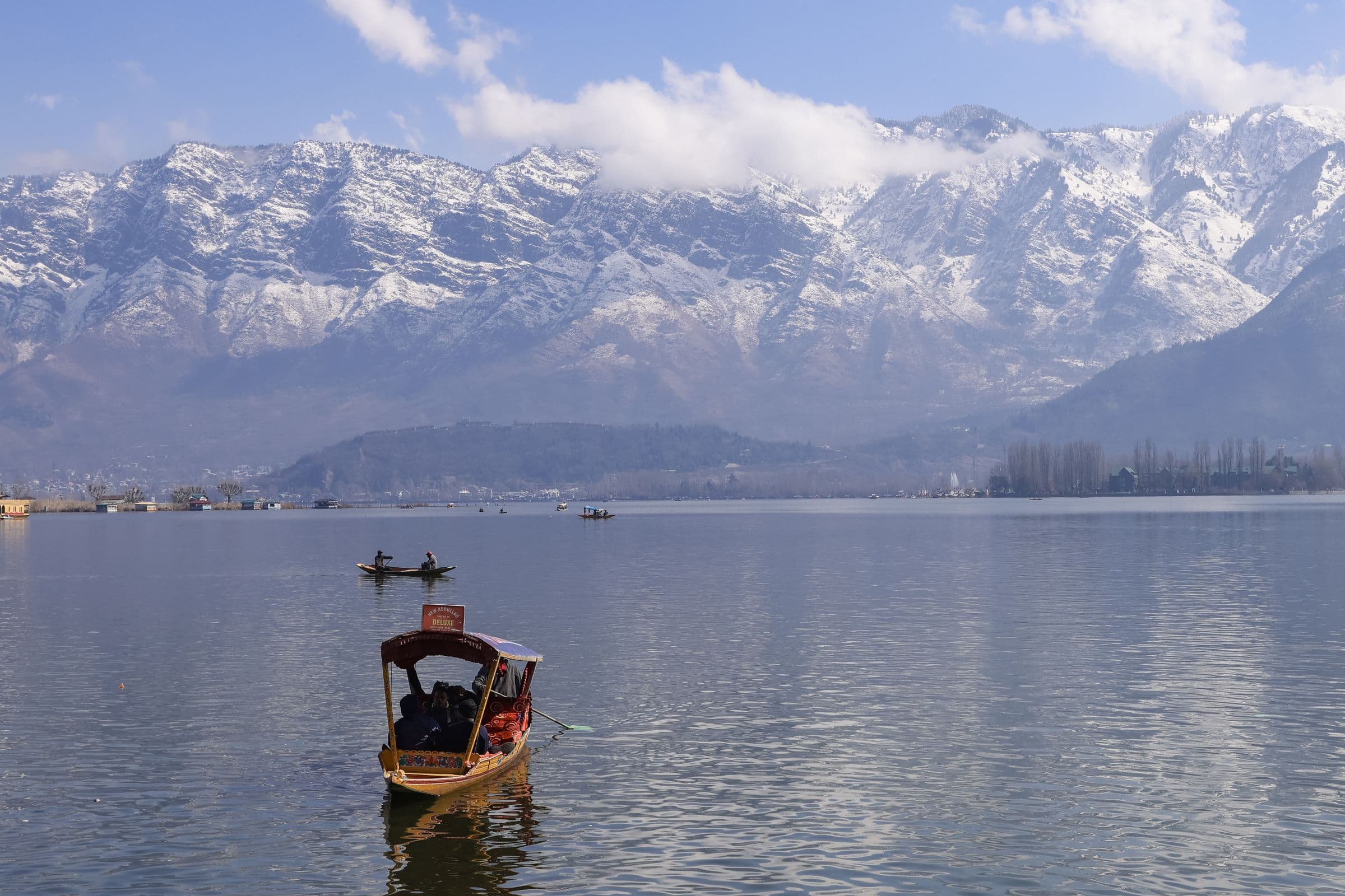 A shikara crossing Dal Lake with the snow-covered Zabarwan range behind Srinagar
